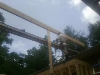 Carpenter setting a ridge beam over a new addition frame in Glencoe